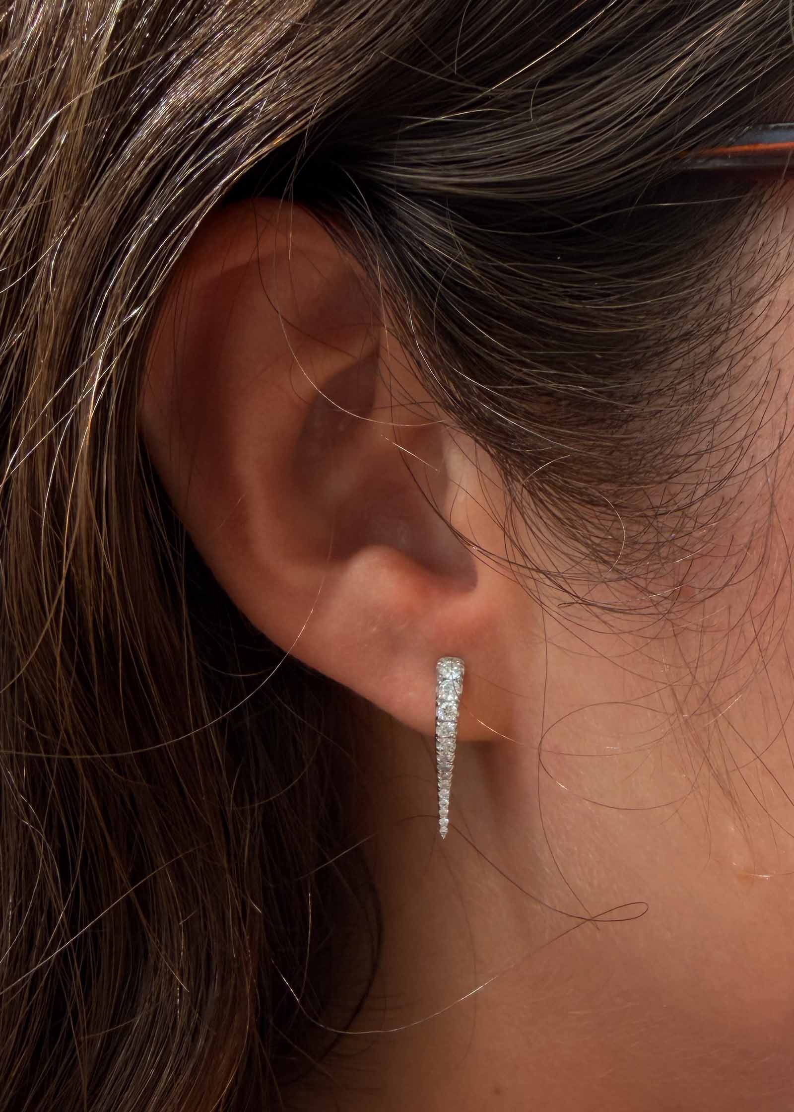 close up of a woman's ear wearing a Kinn x Prince 14k White Gold Point Pavé Diamond Huggie