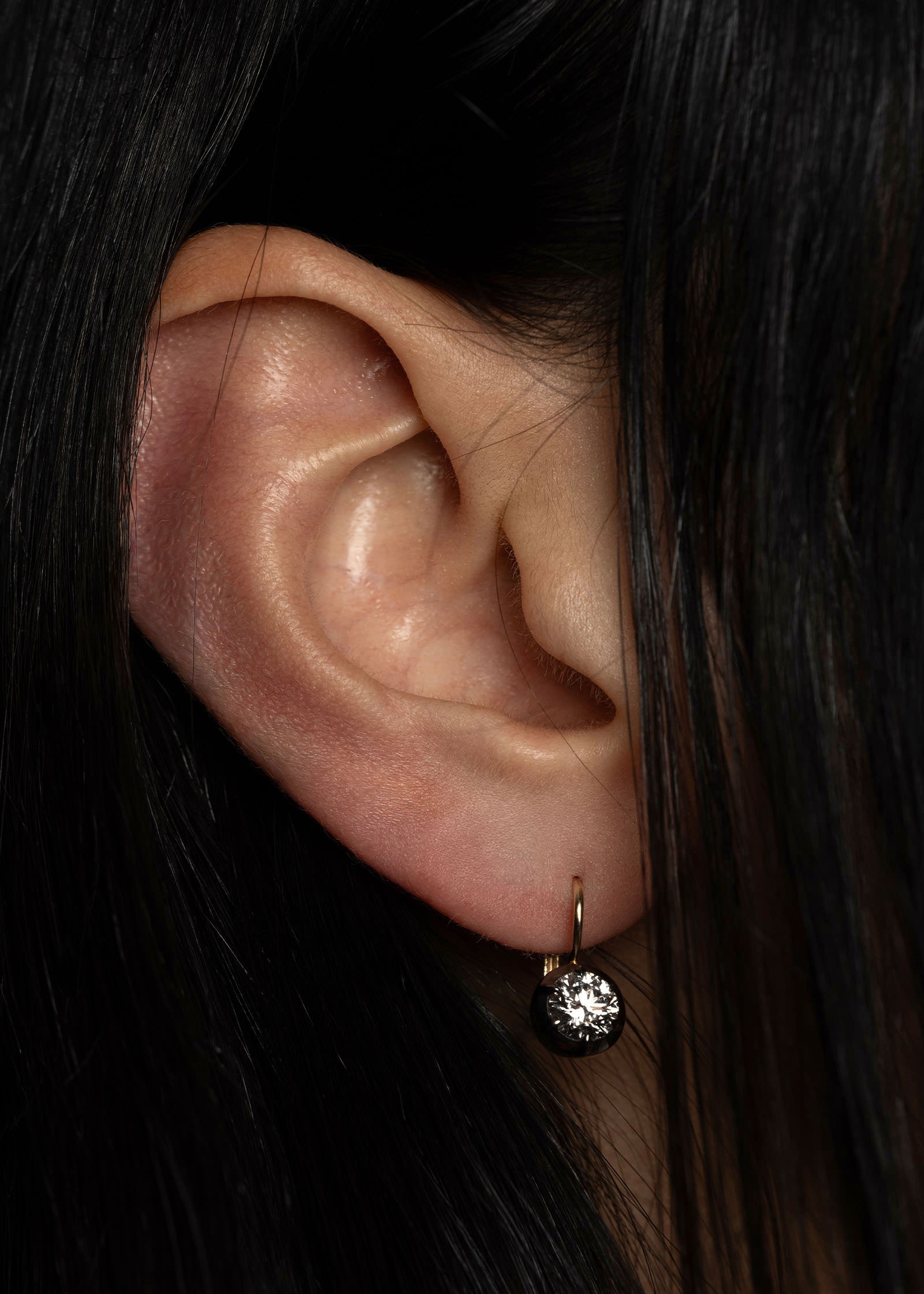 close up of a woman with dark hair wearing a Kinn 14k gold Rosette Black Rhodium Round Diamond Earring