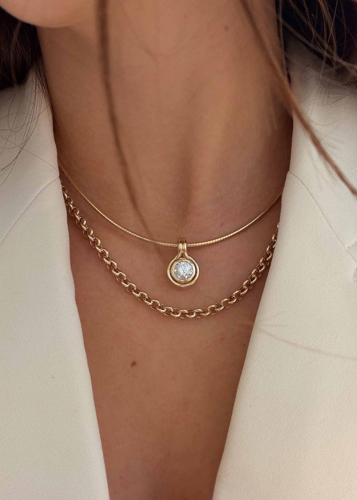 close up of a woman wearing a Kinn Studio 14k Gold Jody Round Diamond Pendant on Heirloom Curved Chain layered with a Matis Rolo Chain necklace
