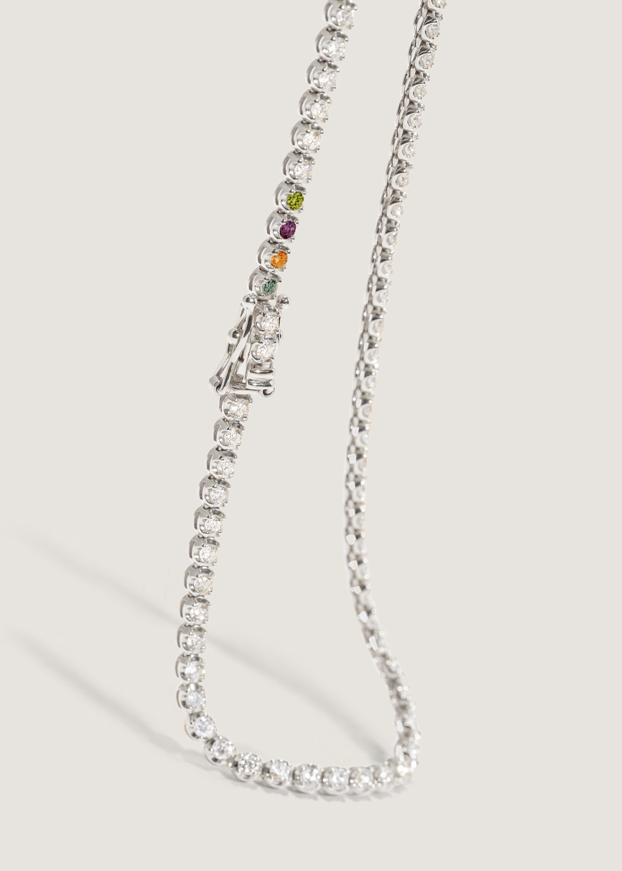 A Kinn 14k gold Madison Diamond Custom Birthstone Tennis Necklace showing four different birthstones near the safety clasp