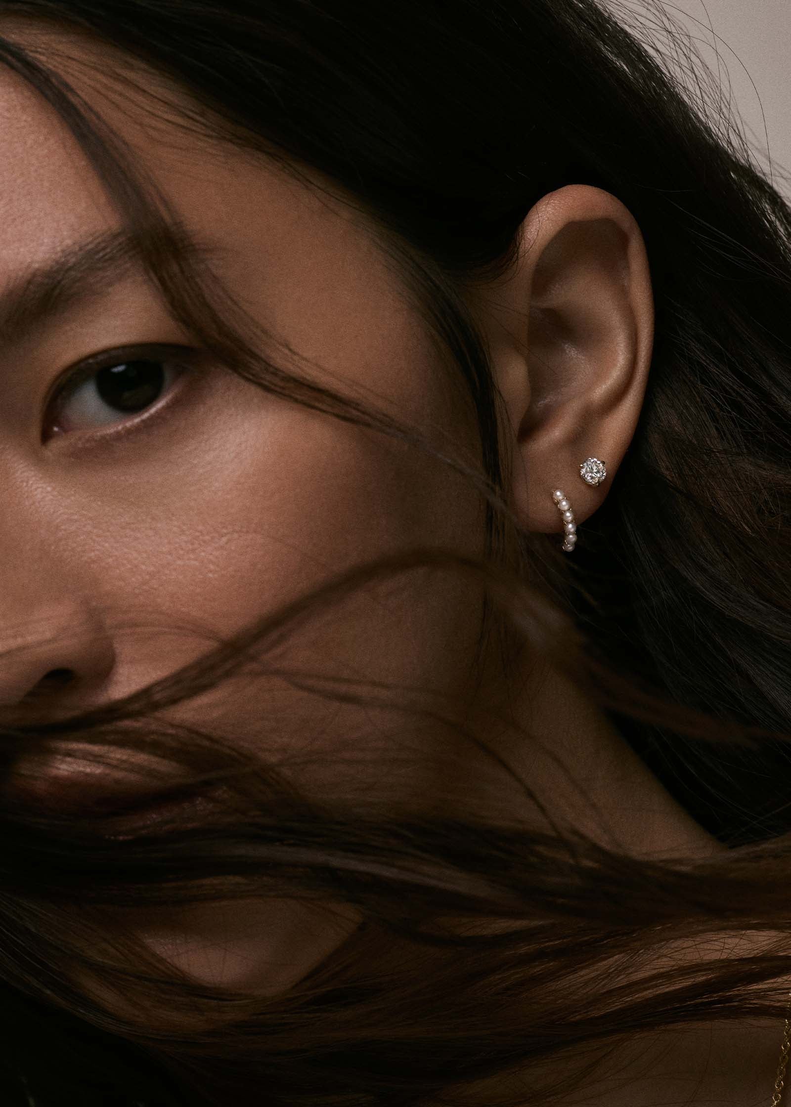 woman wearing a Kinn 14k Gold Marina Pearl Huggie Hoop Earring layered with a June Asscher Diamond Stud