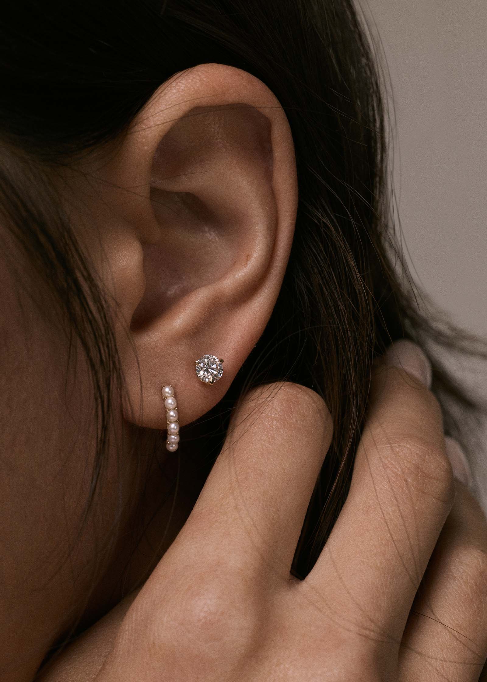 A Kinn 14k Gold Marina Pearl Huggie Hoop Earring layered with a June Round Stud