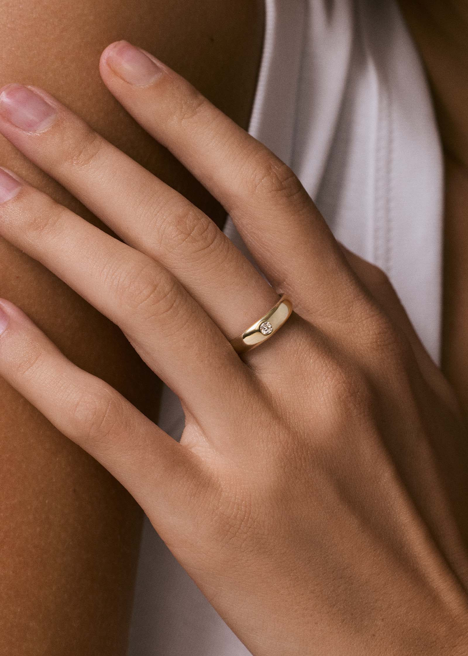 close up of a woman's hand wearing a Kinn 14k Gold Amelia Birthstone Dome Ring Diamond on her ring finger