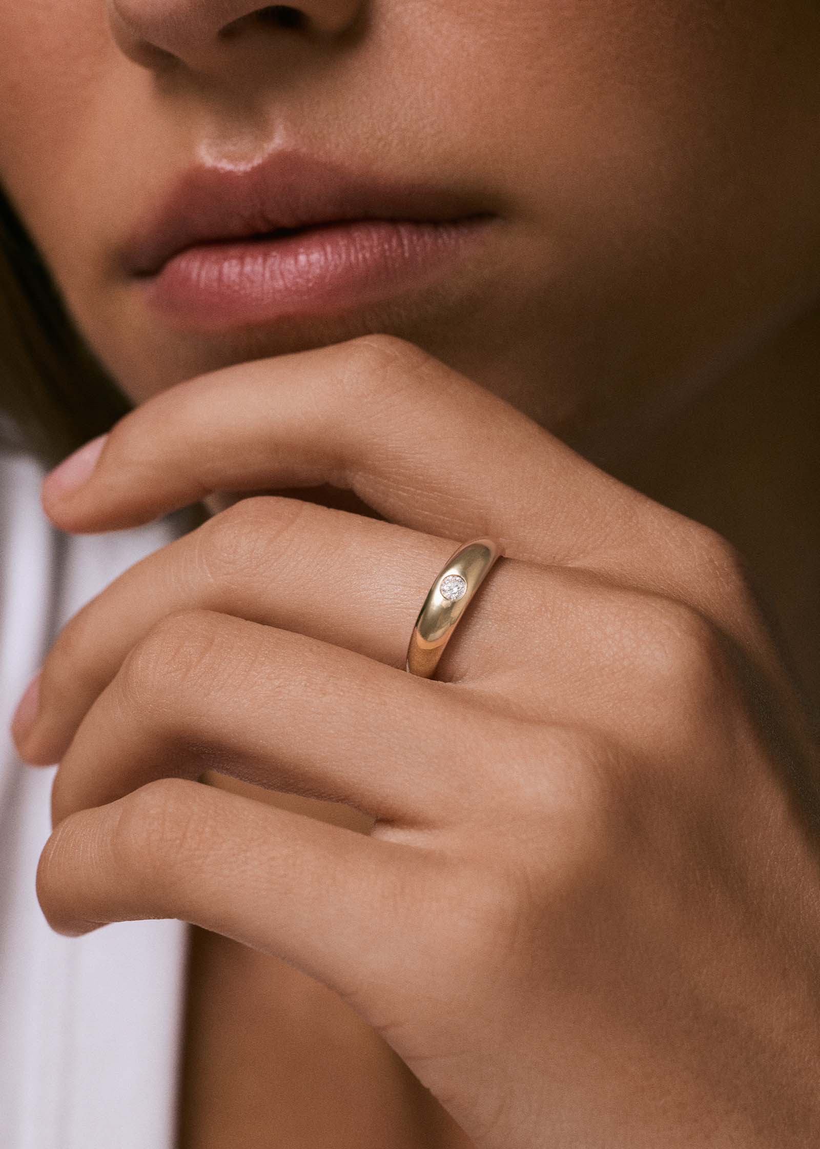 close up of a woman's hand wearing a Kinn 14k Gold Amelia Birthstone Dome Ring Diamond on her ring finger