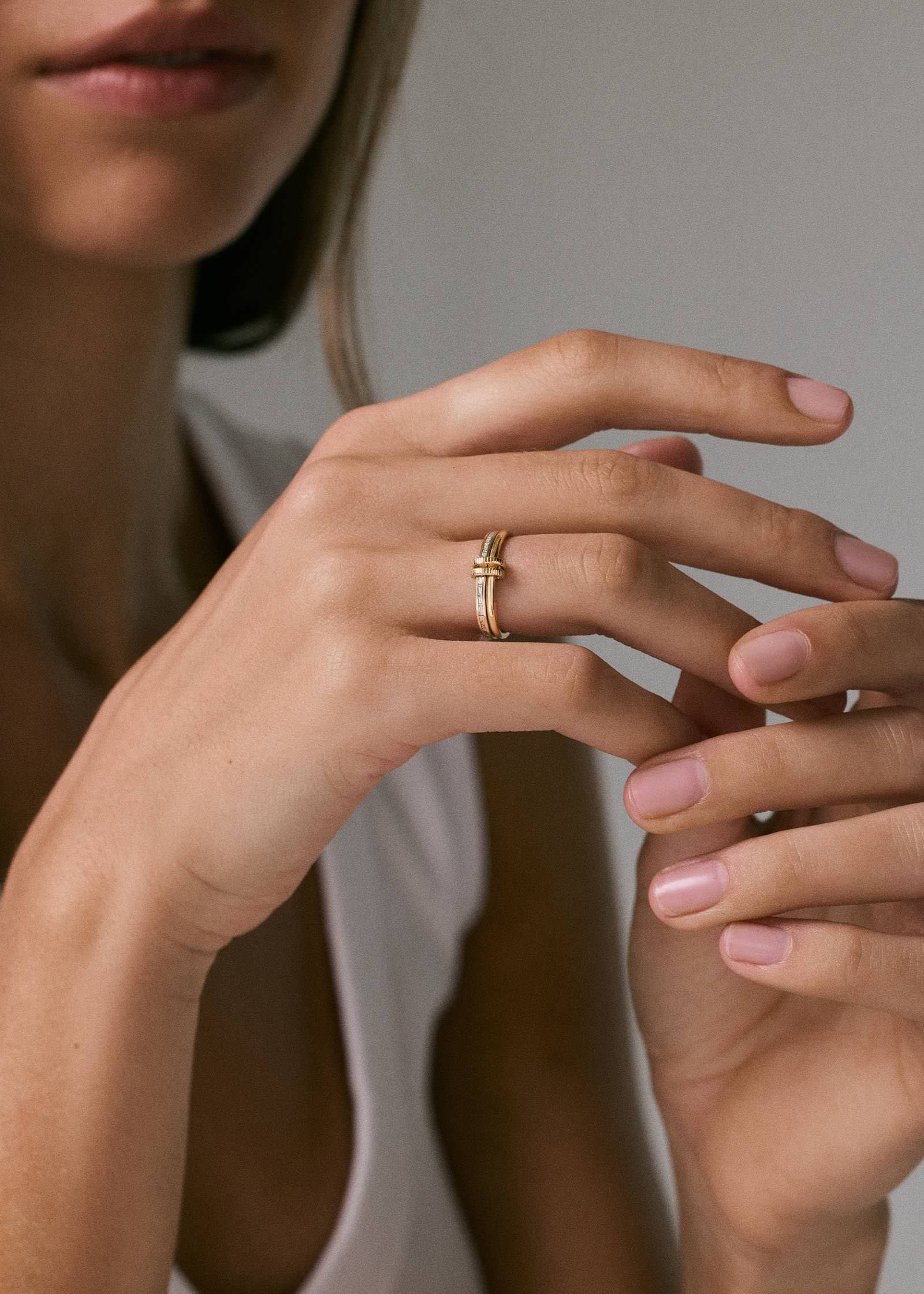woman in a white tank top wearing a Kinn 14k Gold Donna Linked Baguette Band Ring on her ring finger