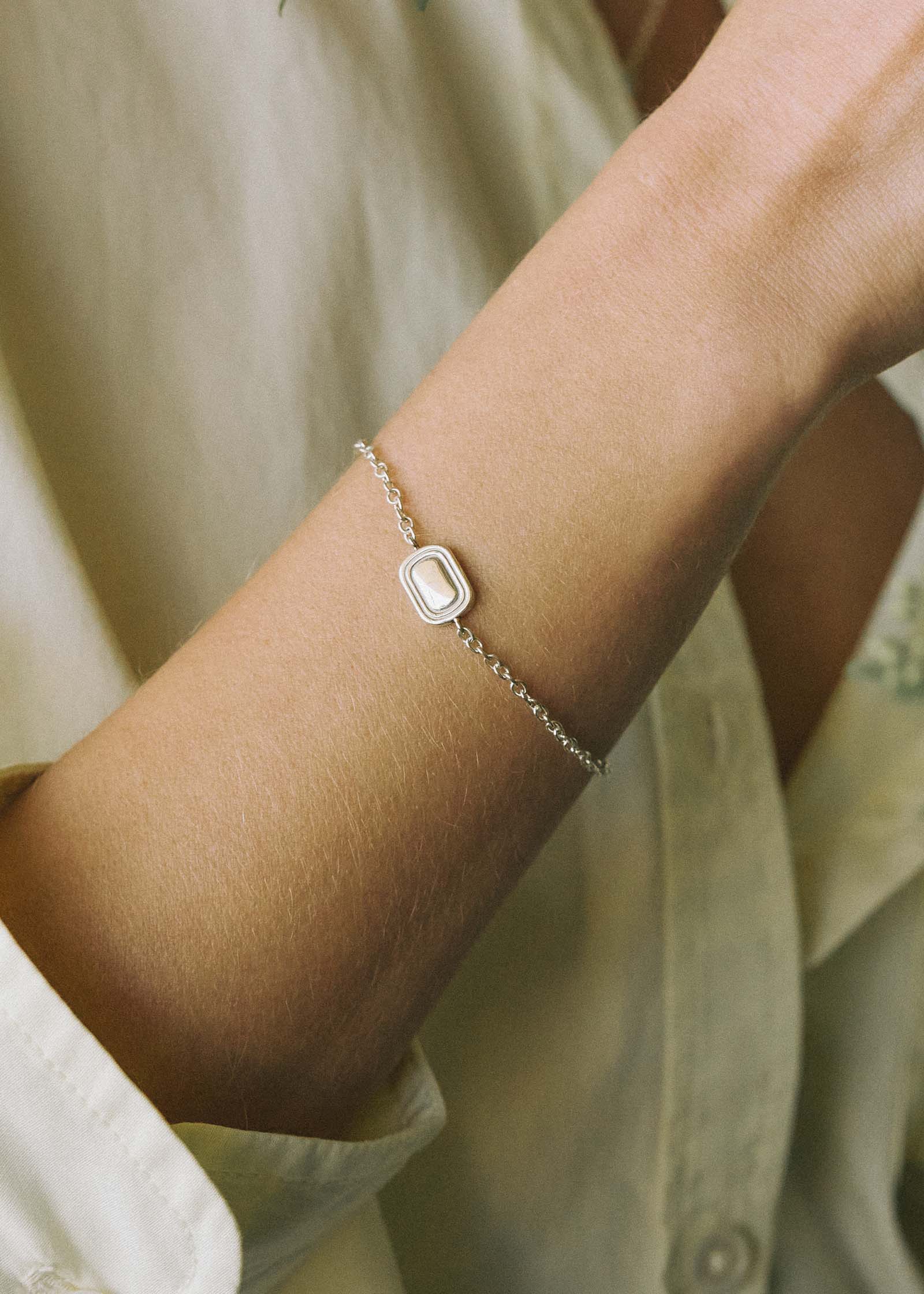 a close up of a woman's arm wearing a Kinn x Shoppe Amber Interiors The Estate Bracelet Sterling Silver and The Estate Signet Ring while she adjusts flowers