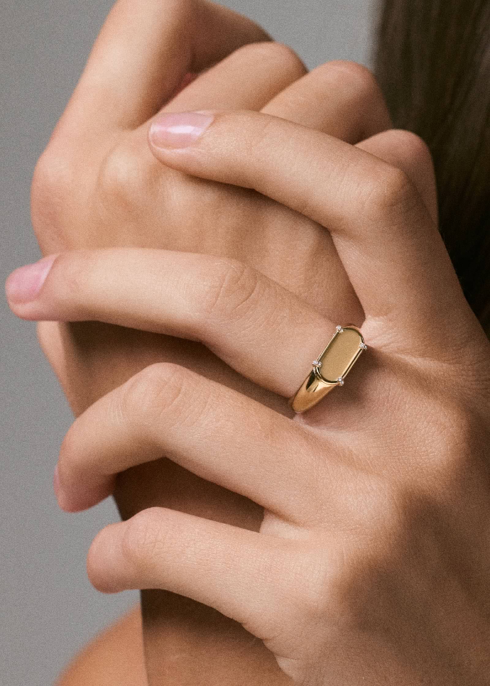 a woman's hand wearing a Kinn 14k gold Harlow Signet Ring Engraved with LS in script font on her middle finger