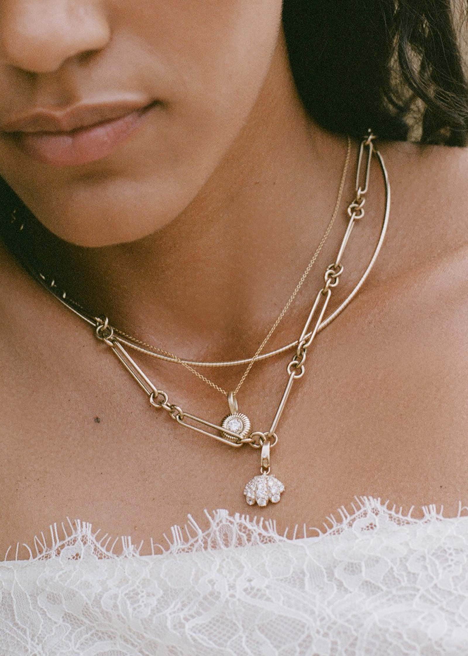 woman wearing a Kinn 14k Gold Pavé Diamond Shell Charm Necklace on Mixed Link Chain layered with an Heirloom Curved Chain Necklace and a Delphe Ribbed Pendant Necklace