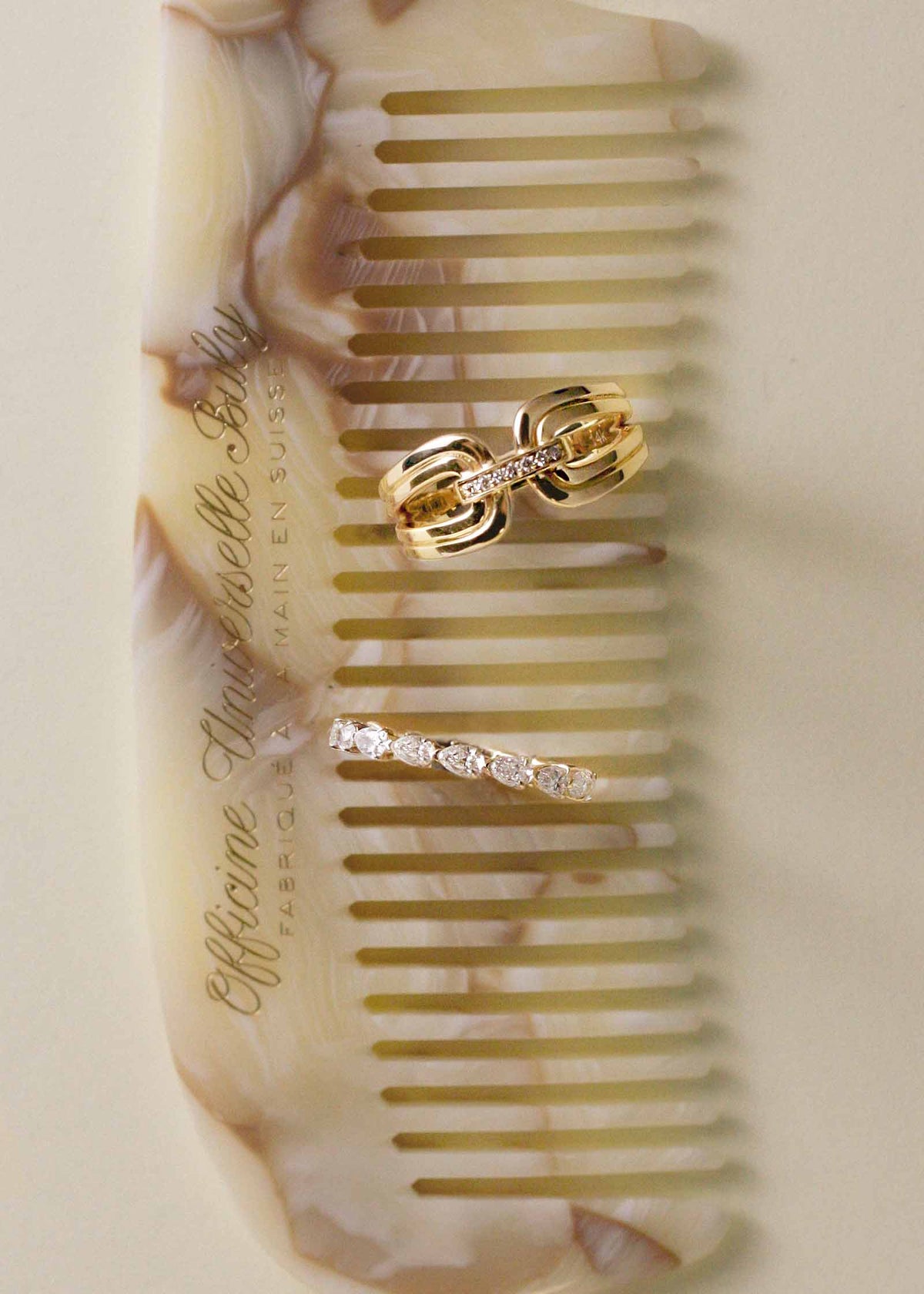 A Kinn 14k Gold Nicky Double Horseshoe Ring and Petite Pear Diamond Eternity Band Ring sitting upright on a comb