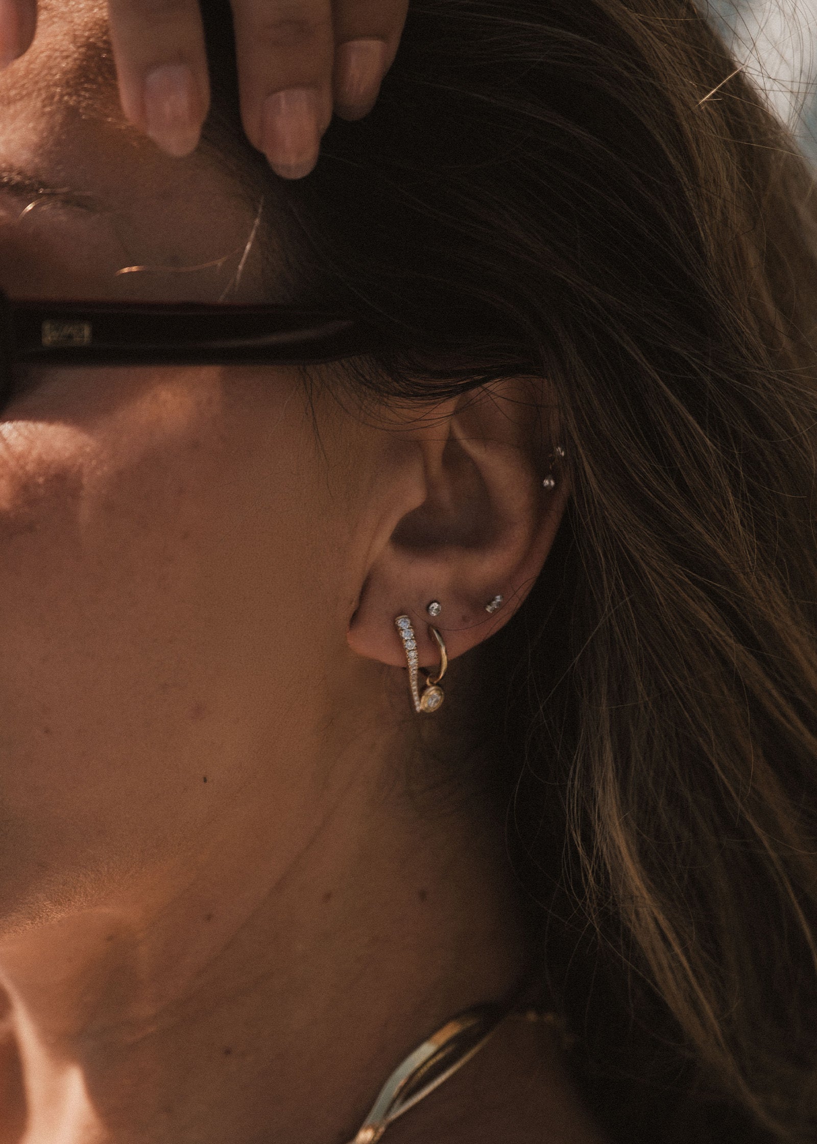 woman wearing a Kinn x Prince 14k Yellow Gold Point Pavé Diamond Huggie layered with a hoop 