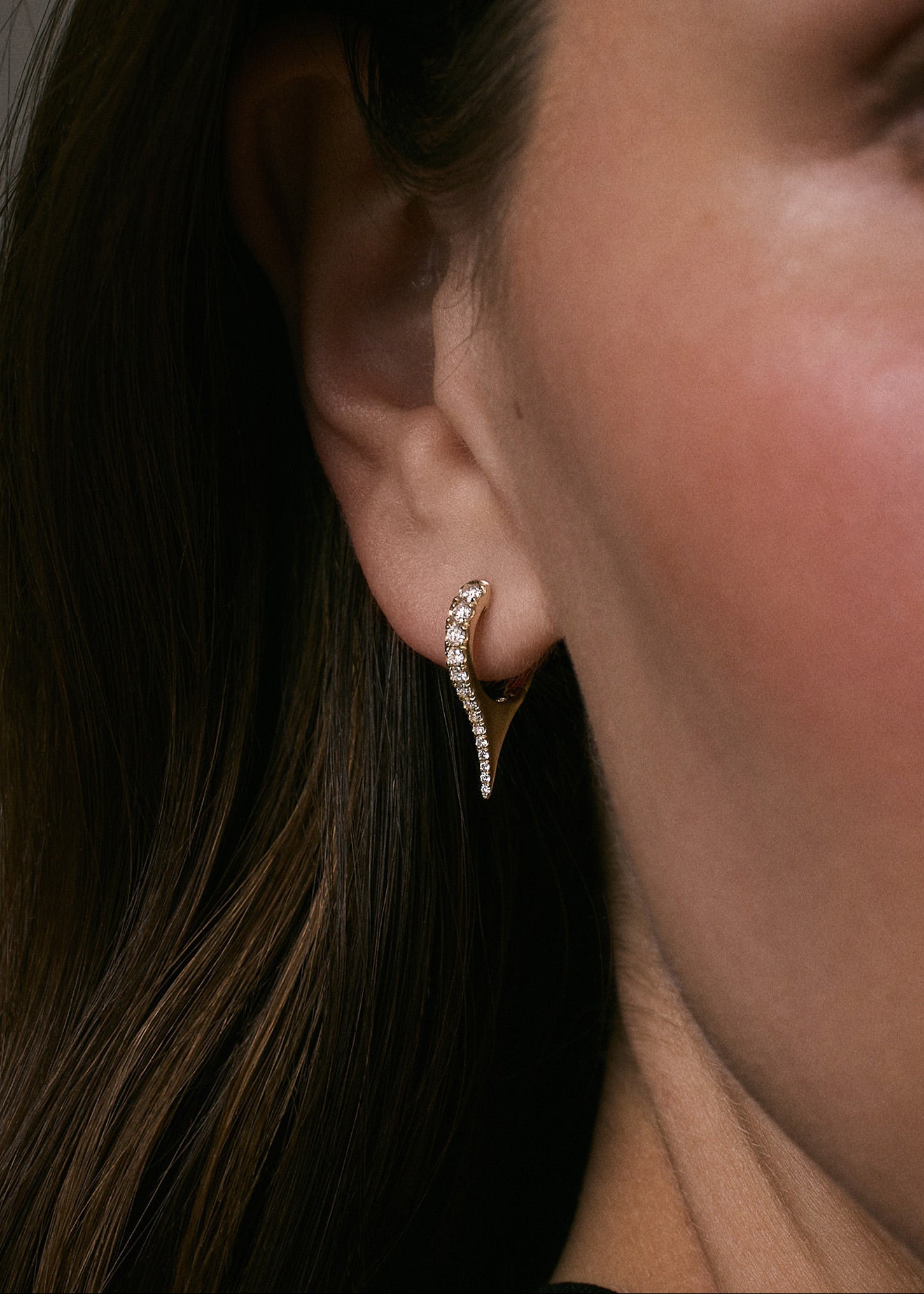 close up of woman's ear wearing a Kinn x Prince 14k Yellow Gold Point Pavé Diamond Huggie showing an angled view