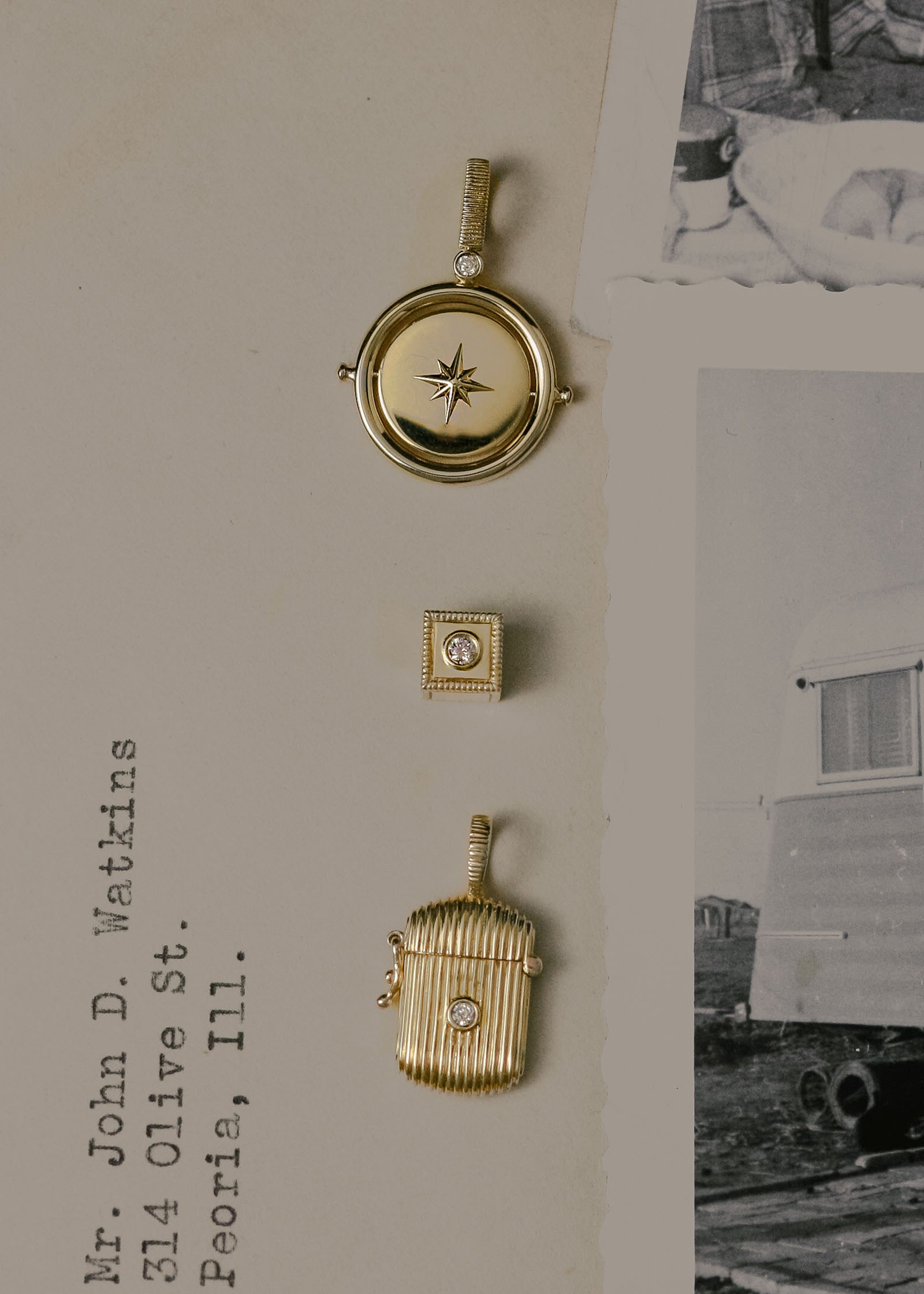A Kinn 14k Gold Round North Star Birthstone Diamond Pendant, Chapter Custom Birthstone Charm, and a Relic Ribbed Diamond Locket Pendant laying in a row flat against a letter with black and white photographs