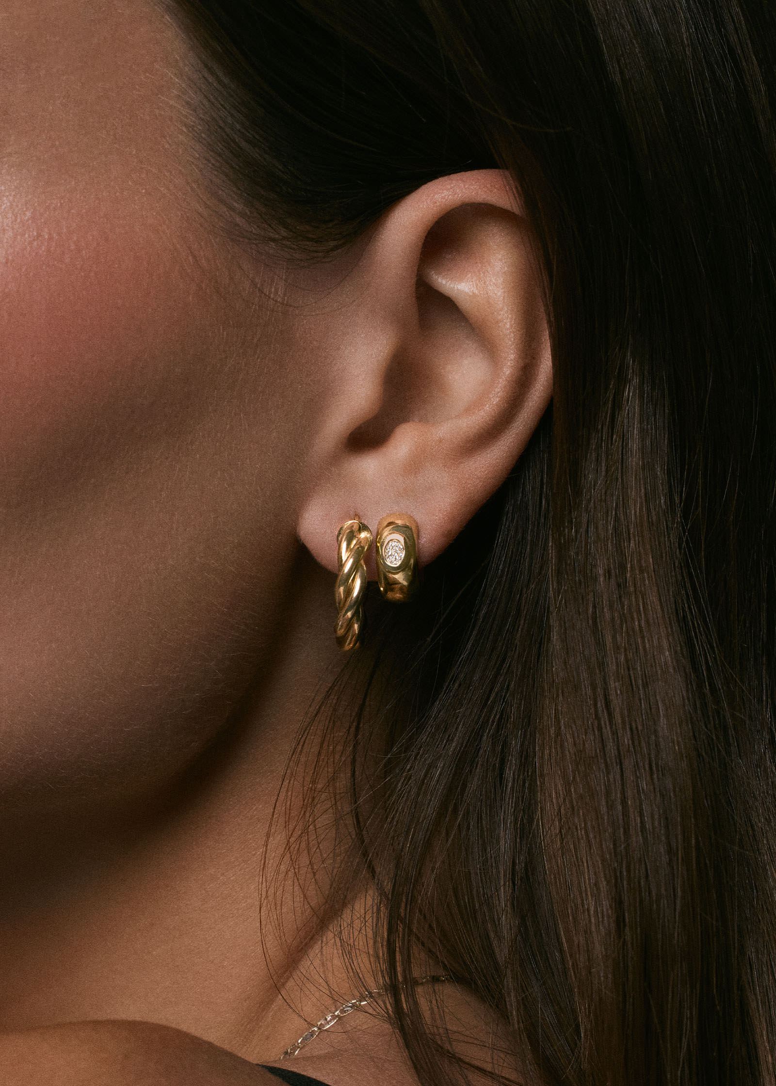 woman wearing a Kinn 14k Gold Taylor Twist Petite Hoop Earring layered with a Ynez Dome Huggie Earrings Diamond 