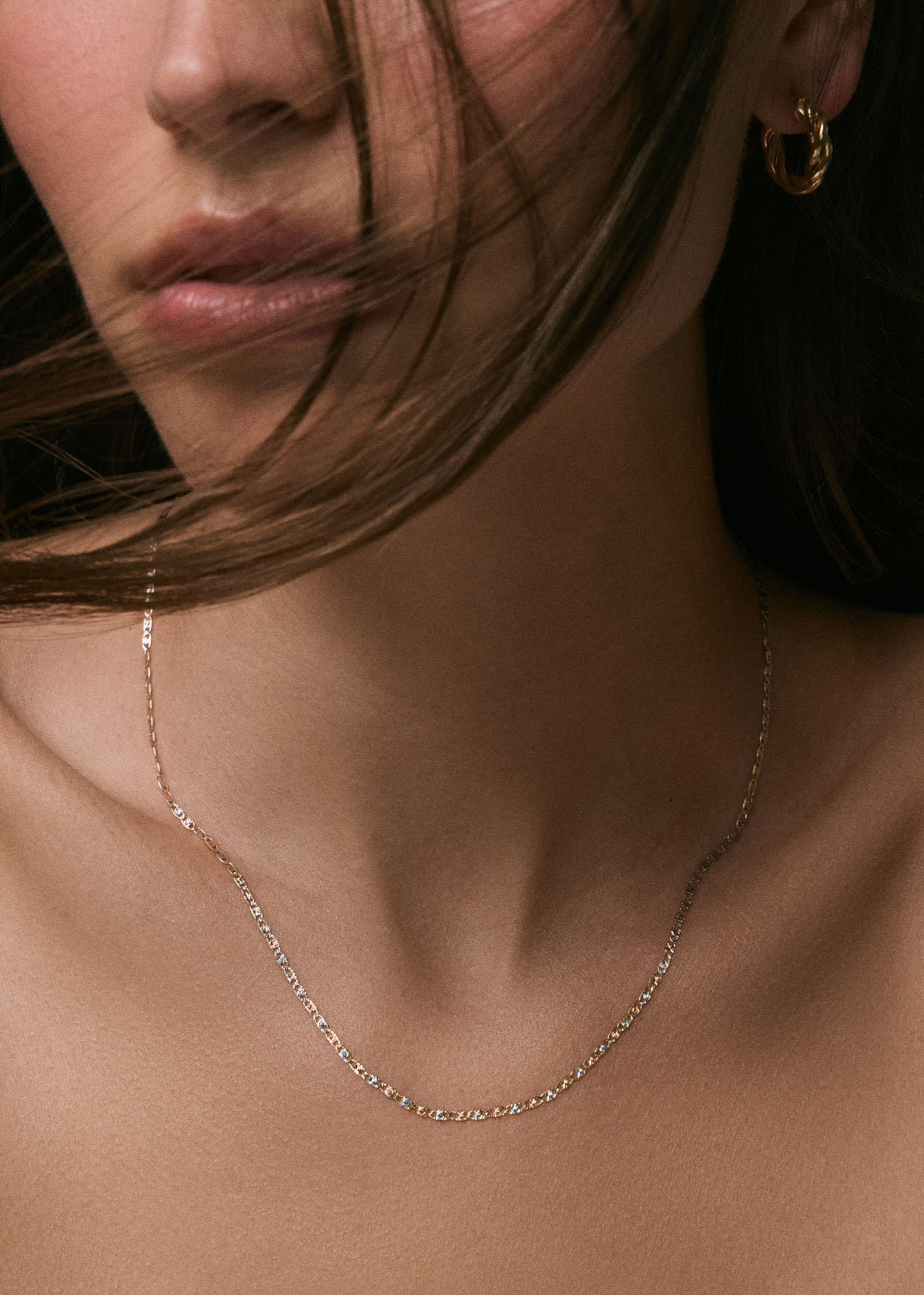 A woman wearing a A Kinn 14k Valentino Tri-Color Gold Chain Necklace