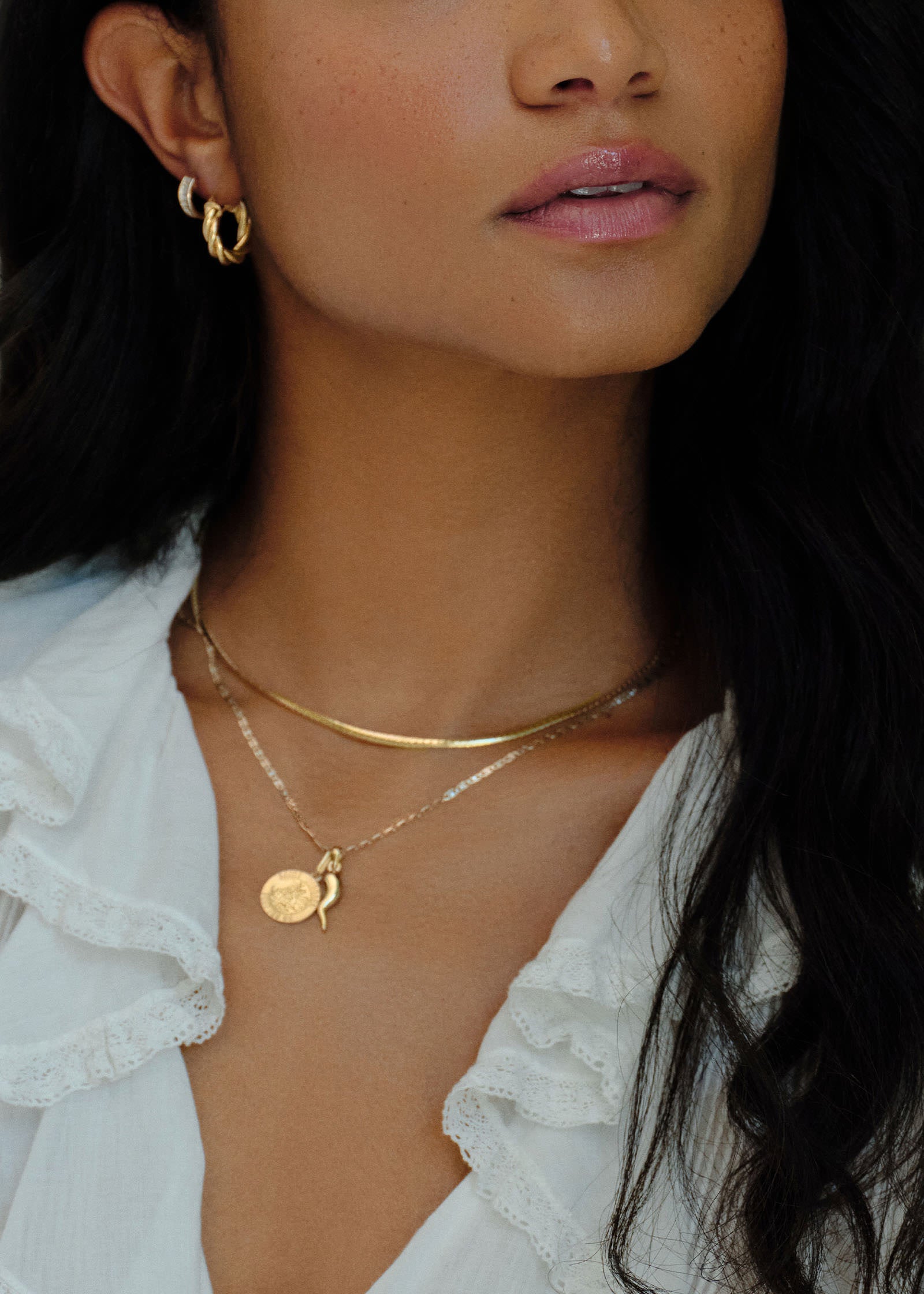 woman wearing a Kinn 14k Valentino Tri-Color Gold Chain Necklace with a Saint Michael and Cornicello Pendant hanging from the chain layered with an Heirloom Curved Chain Necklace