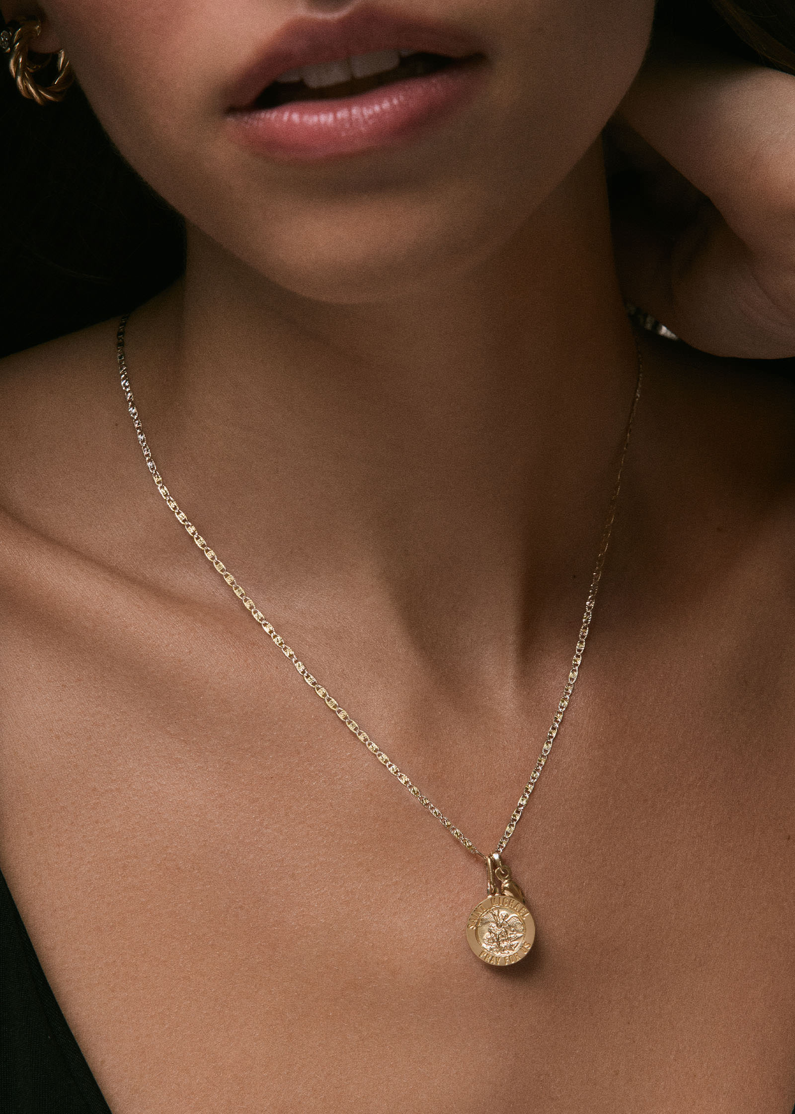 close up of a woman wearing a Kinn 14k Valentino Tri-Color Gold Chain Necklace and a 14k Gold Saint Michael Pendant