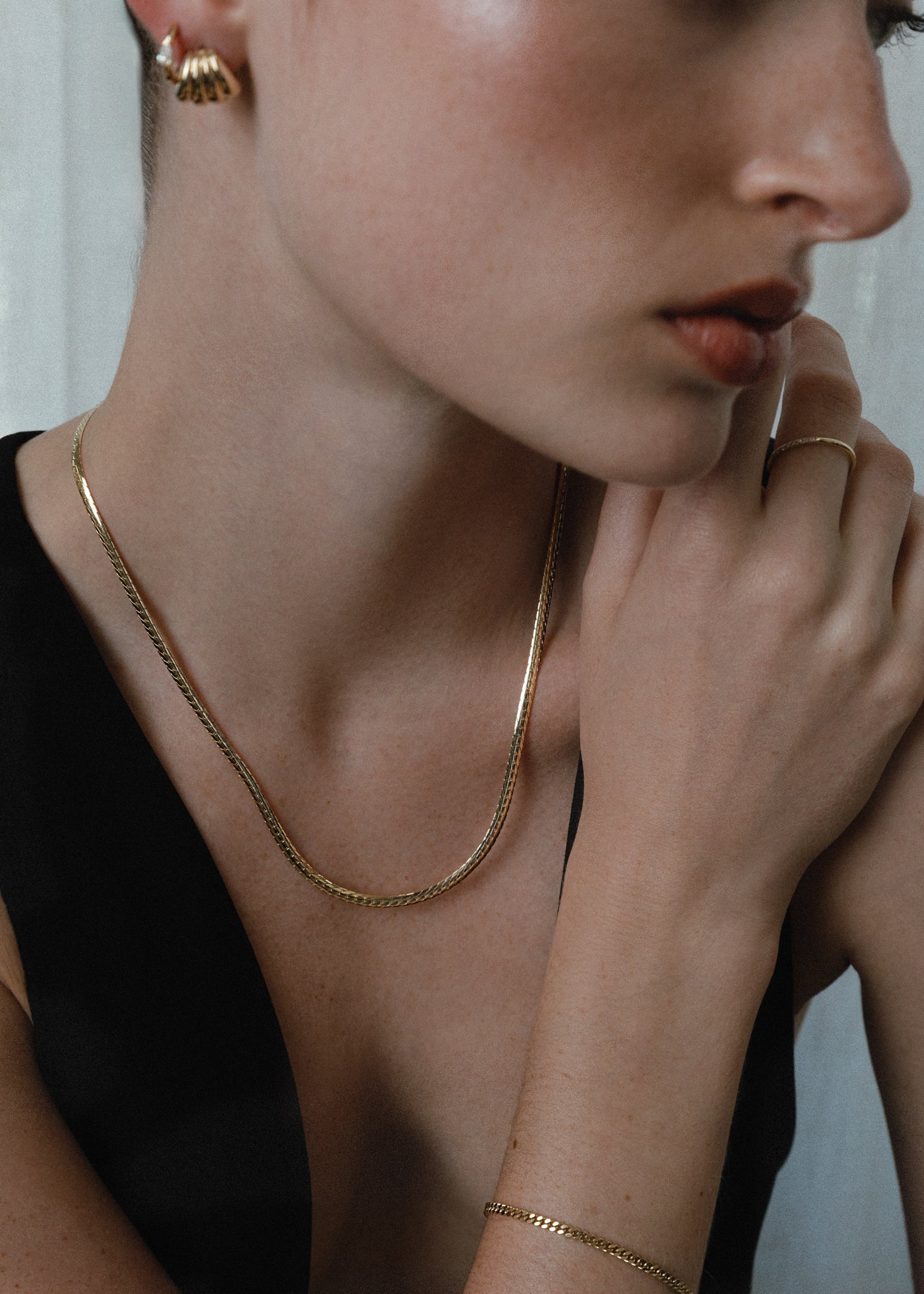 A woman wearing a Kinn 14k Gold Kennedy Herringbone Chain Necklace