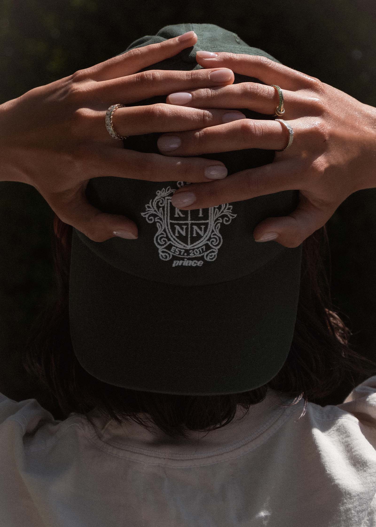 woman wearing a backwards Kinn x Prince The Club Cap holding her hands behind her head