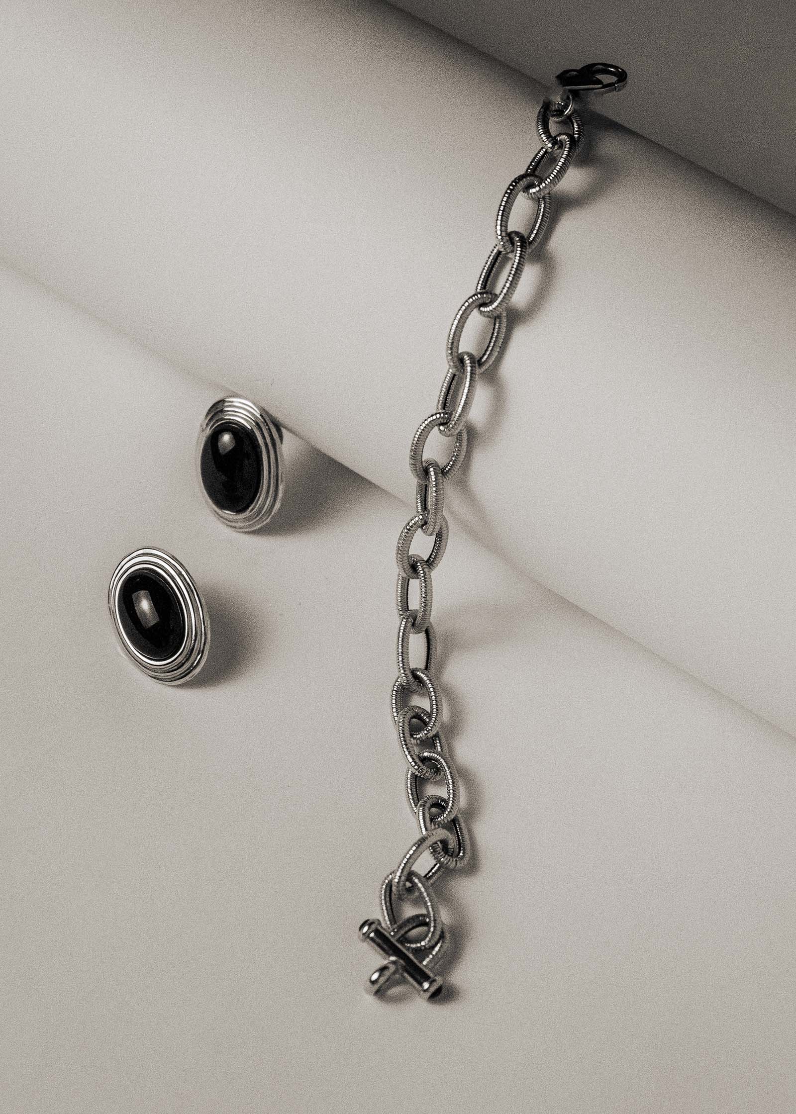 black and white photo of Kinn Vintage 14k Gold Oval Onyx Earrings laid next to a vintage bracelet