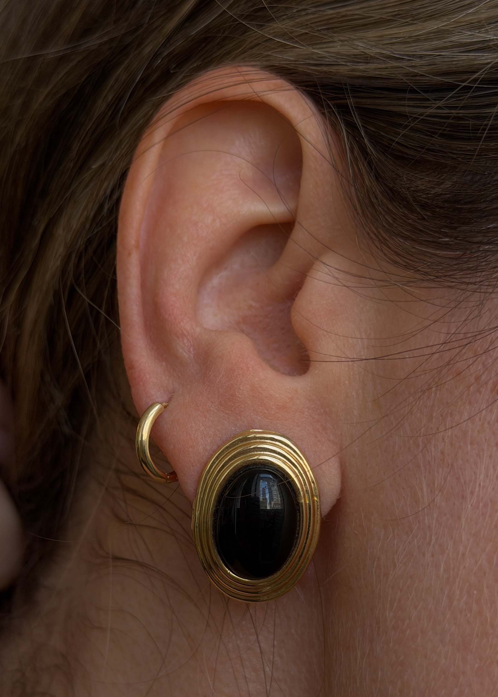 close up of the Kinn Vintage 14k Gold Oval Onyx Earrings worn on ear