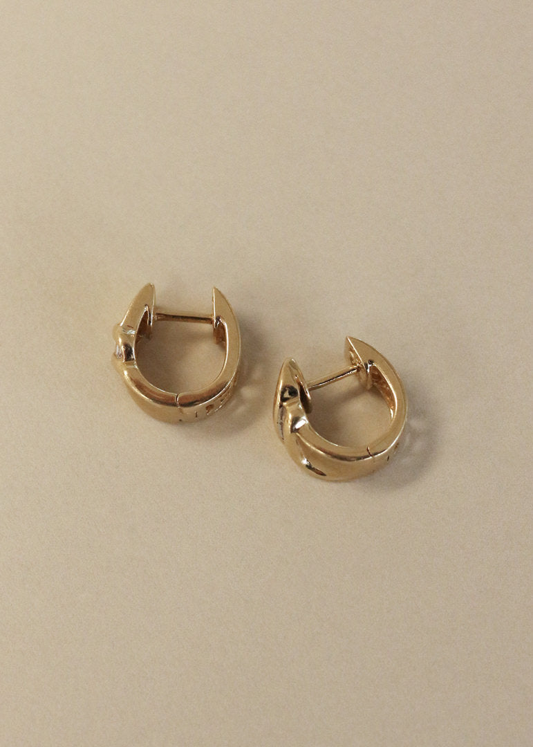 Side view of a pair of Kinn Vintage 14k Gold Baguette Diamond Huggie Earrings
