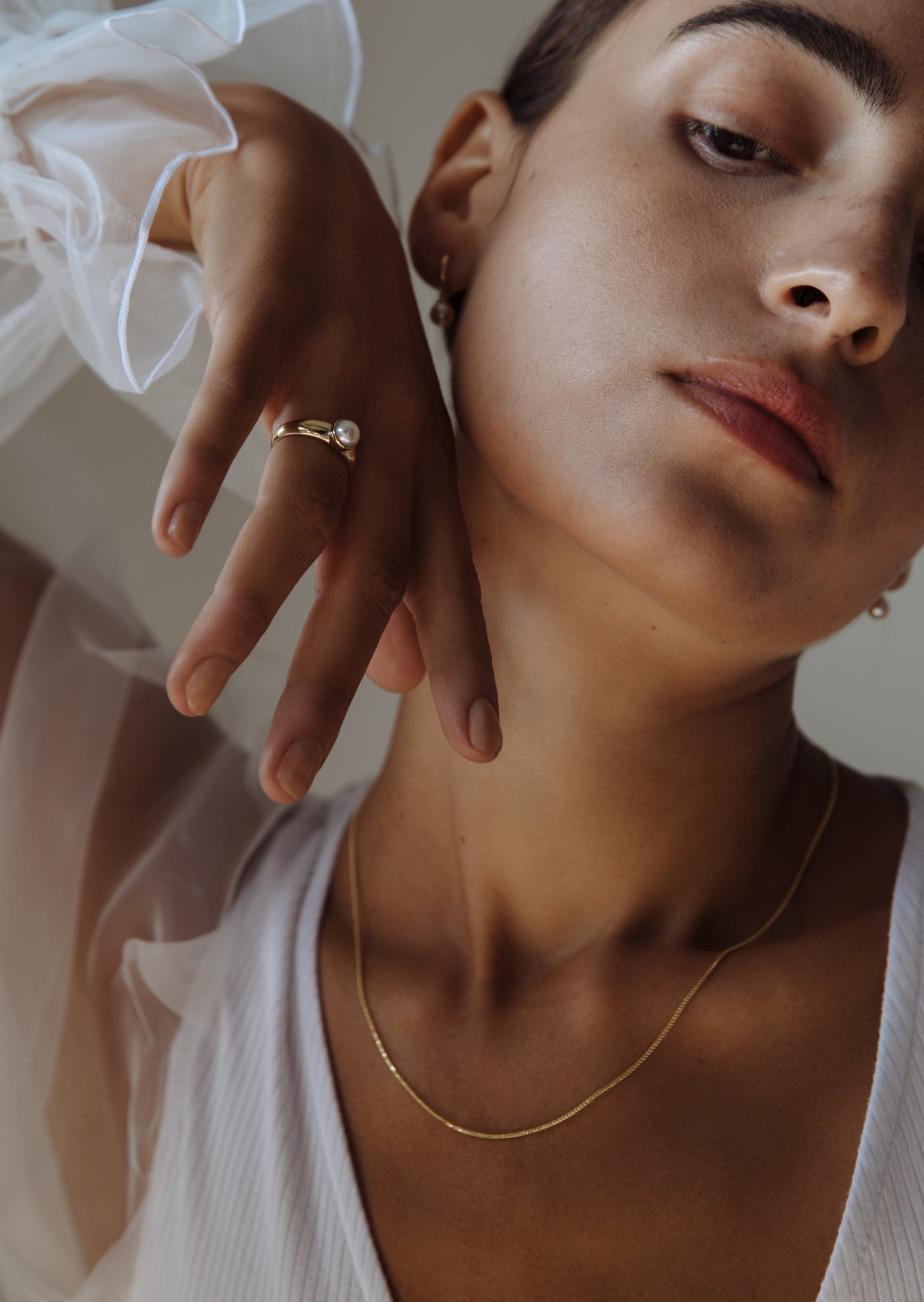 woman with her hand raised up wearing a Kinn 14k Gold Pearl Signet Ring on her ring finger